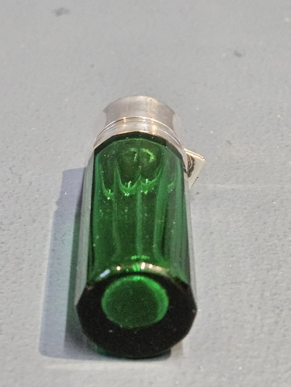 A cylindrical emerald green faceted glass scent bottle featuring a smooth silver cap stamped with hallmarks. View VI