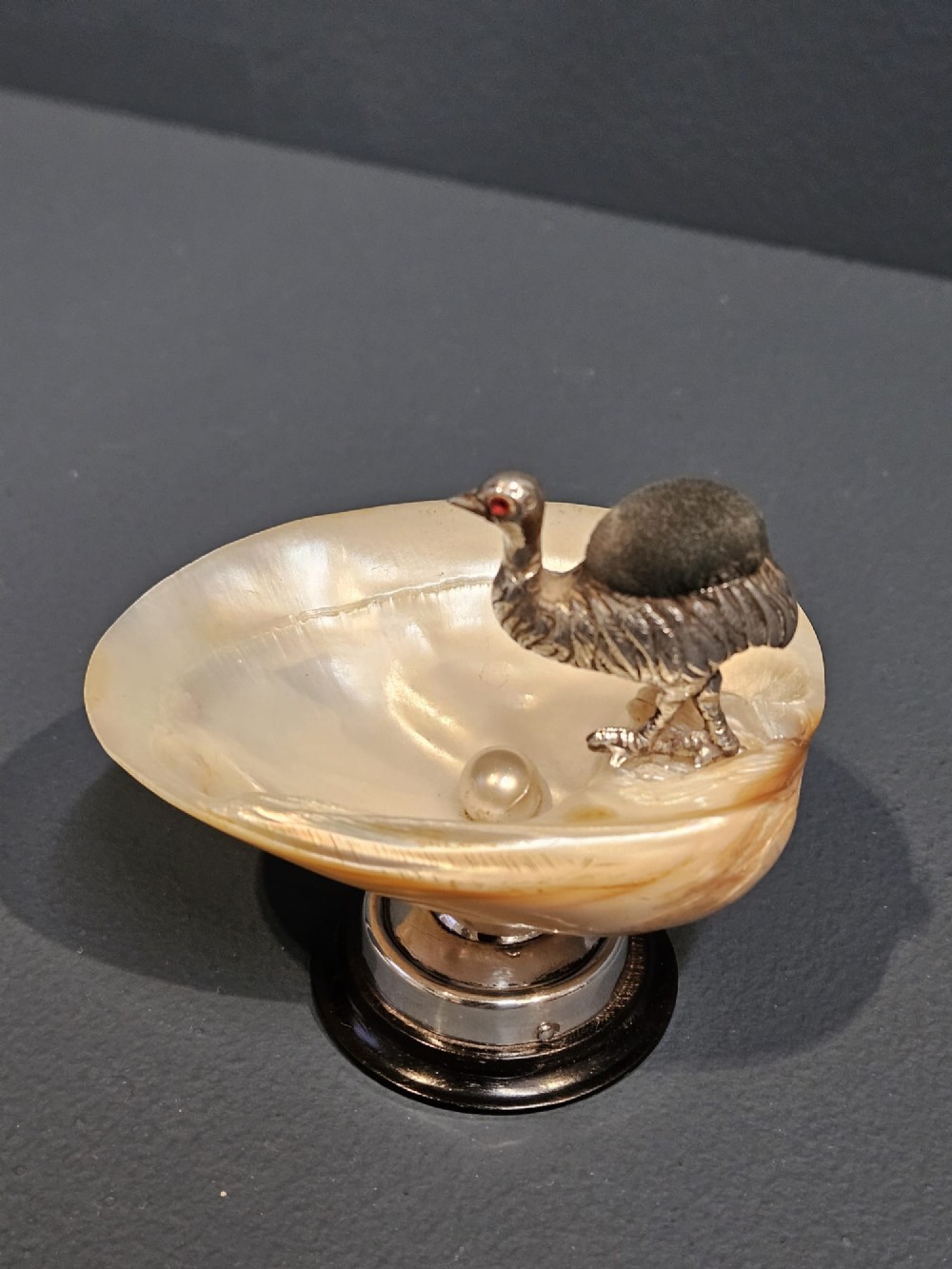 An Edwardian sterling silver emu figurine with an embedded fabric pin cushion, mounted on a polished mother-of-pearl shell dish. View II