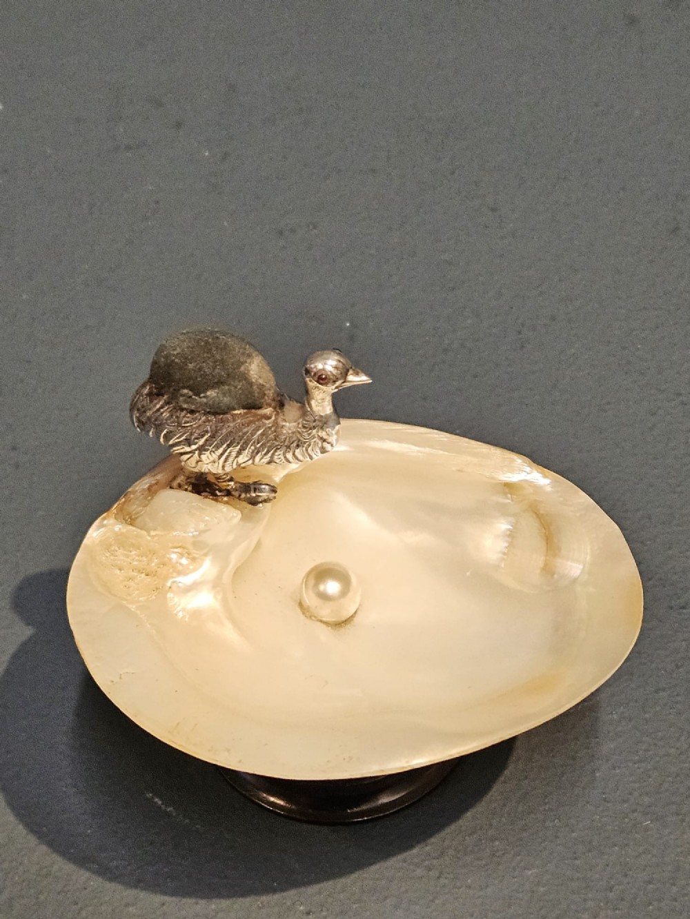 An Edwardian sterling silver emu figurine with an embedded fabric pin cushion, mounted on a polished mother-of-pearl shell dish. View V