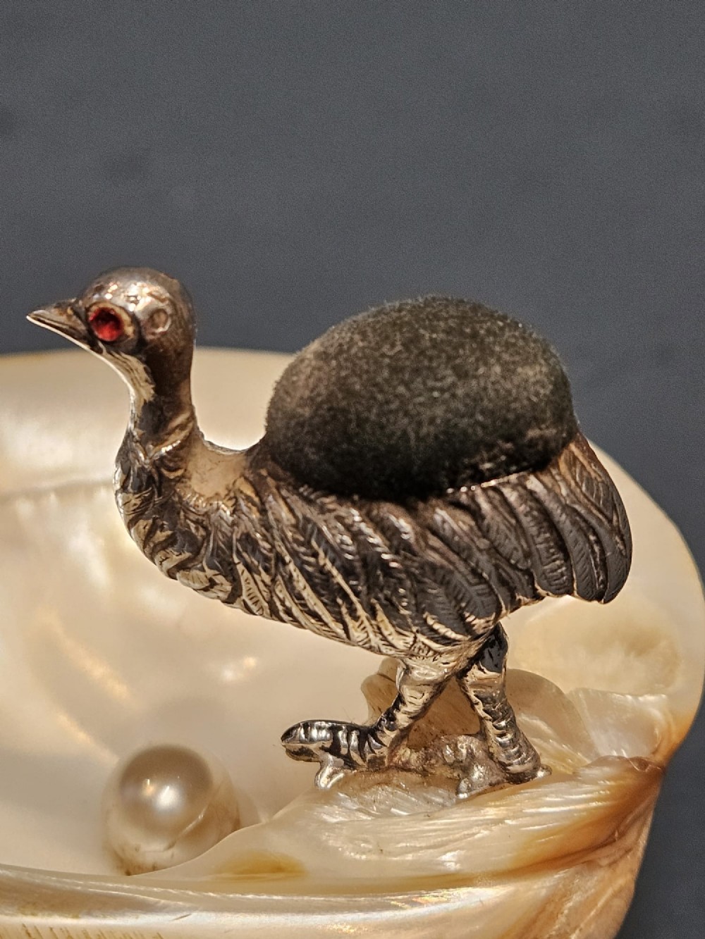 An Edwardian sterling silver emu figurine with an embedded fabric pin cushion, mounted on a polished mother-of-pearl shell dish. View VI
