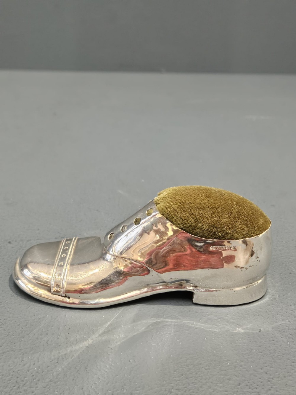 An Edwardian hallmarked sterling silver pin cushion shaped like a gentlemans shoe with an olive green velvet cushion top. View IV