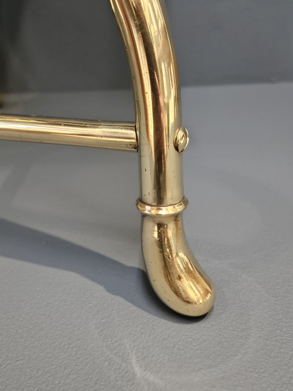 A Victorian revolving book stand featuring a polished brass wire rack mounted on a square oak surface supported by a brass tripod base. View V