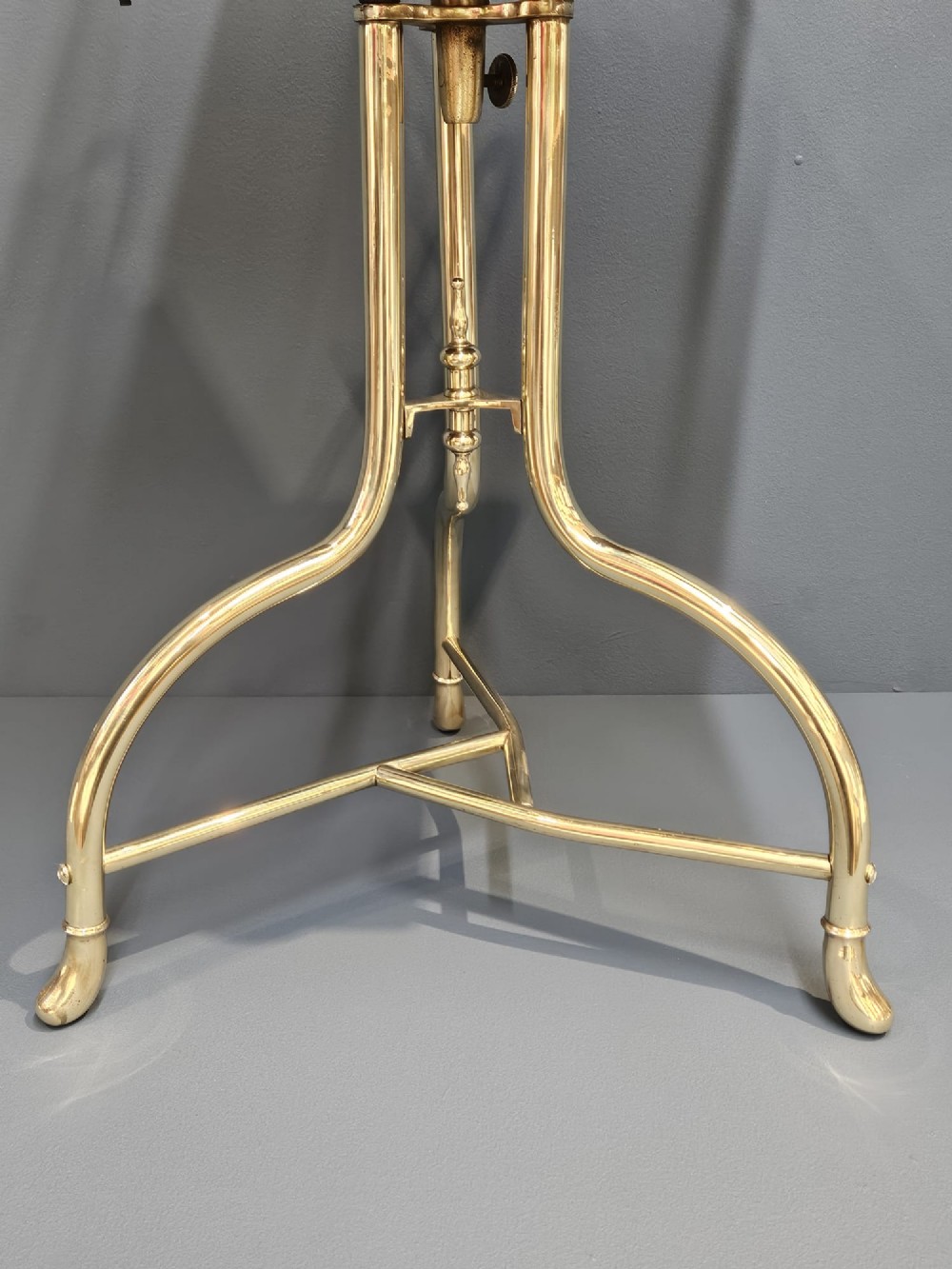 A Victorian revolving book stand featuring a polished brass wire rack mounted on a square oak surface supported by a brass tripod base. View VIII