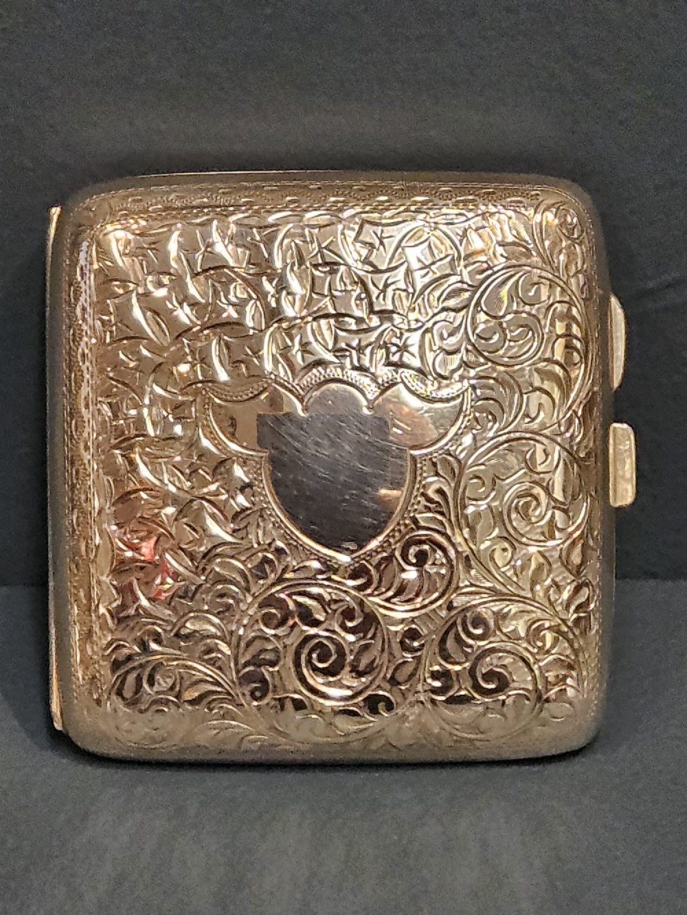 A square metallic silver pocket case featuring detailed chased foliate scrollwork and a central blank cartouche. View II