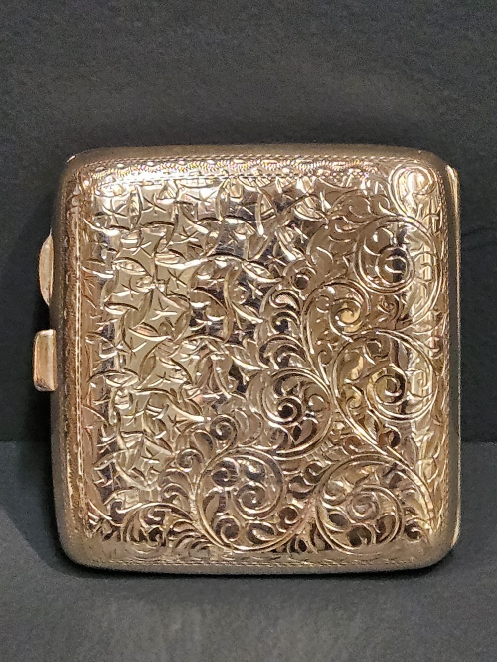 A square metallic silver pocket case featuring detailed chased foliate scrollwork and a central blank cartouche. View III