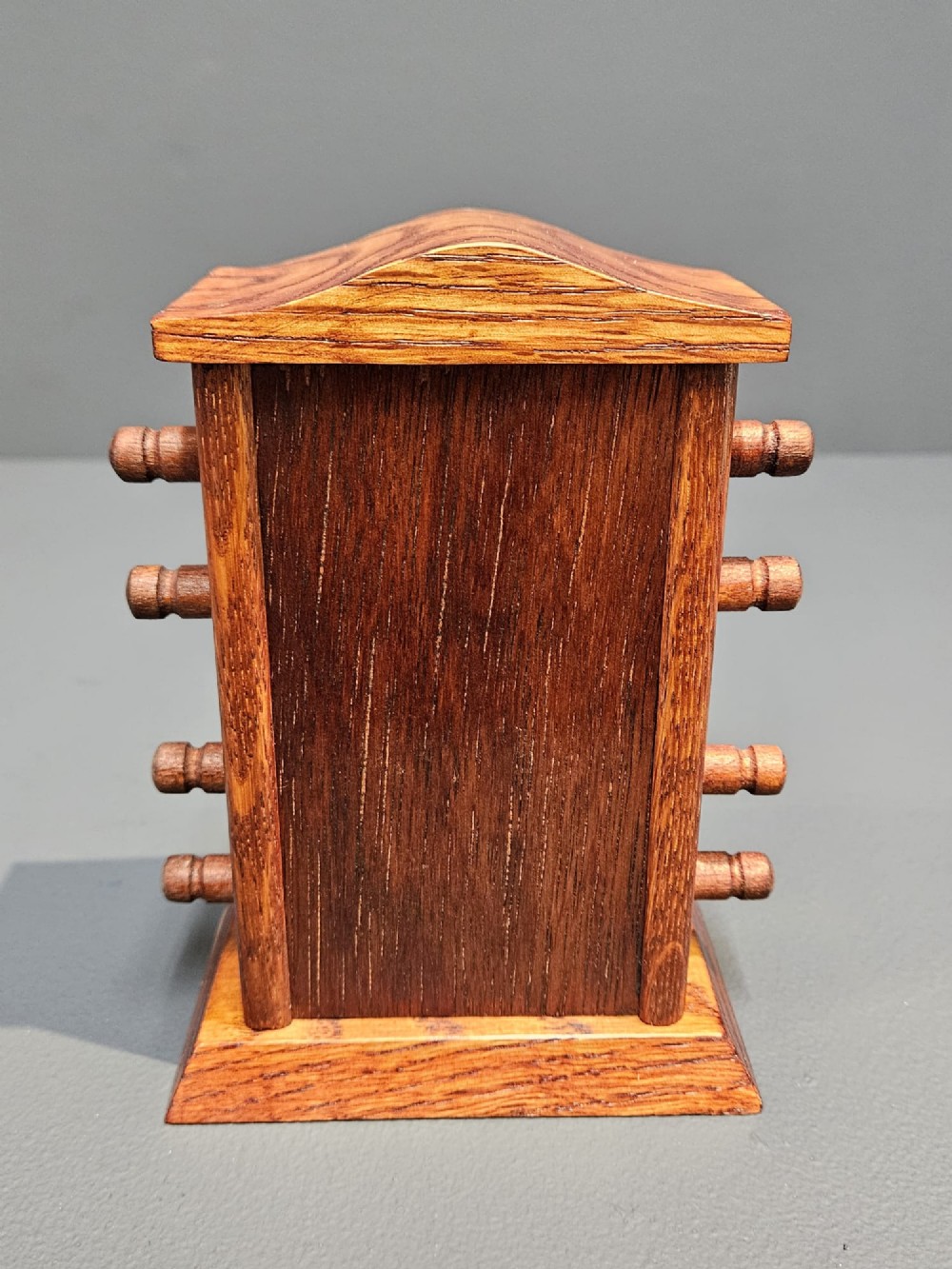 An Edwardian carved oak perpetual desk calendar featuring side turning pegs and printed linen date scrolls behind rectangular window openings. View V
