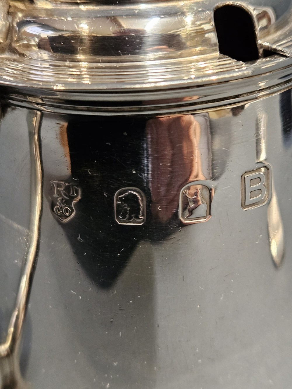 A cylindrical Britannia silver mustard pot featuring a scalloped collar rim, stepped lid with shell finial, and an inserted silver spoon. View VI