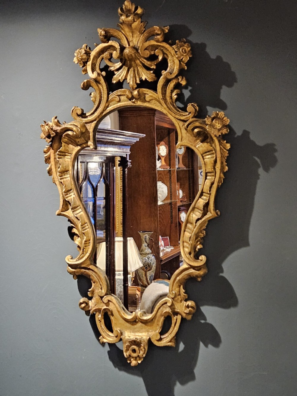 A mid-Victorian lozenge-shaped wall mirror featuring an ornate gold leaf giltwood frame decorated with scrolls and acanthus leaf cresting.