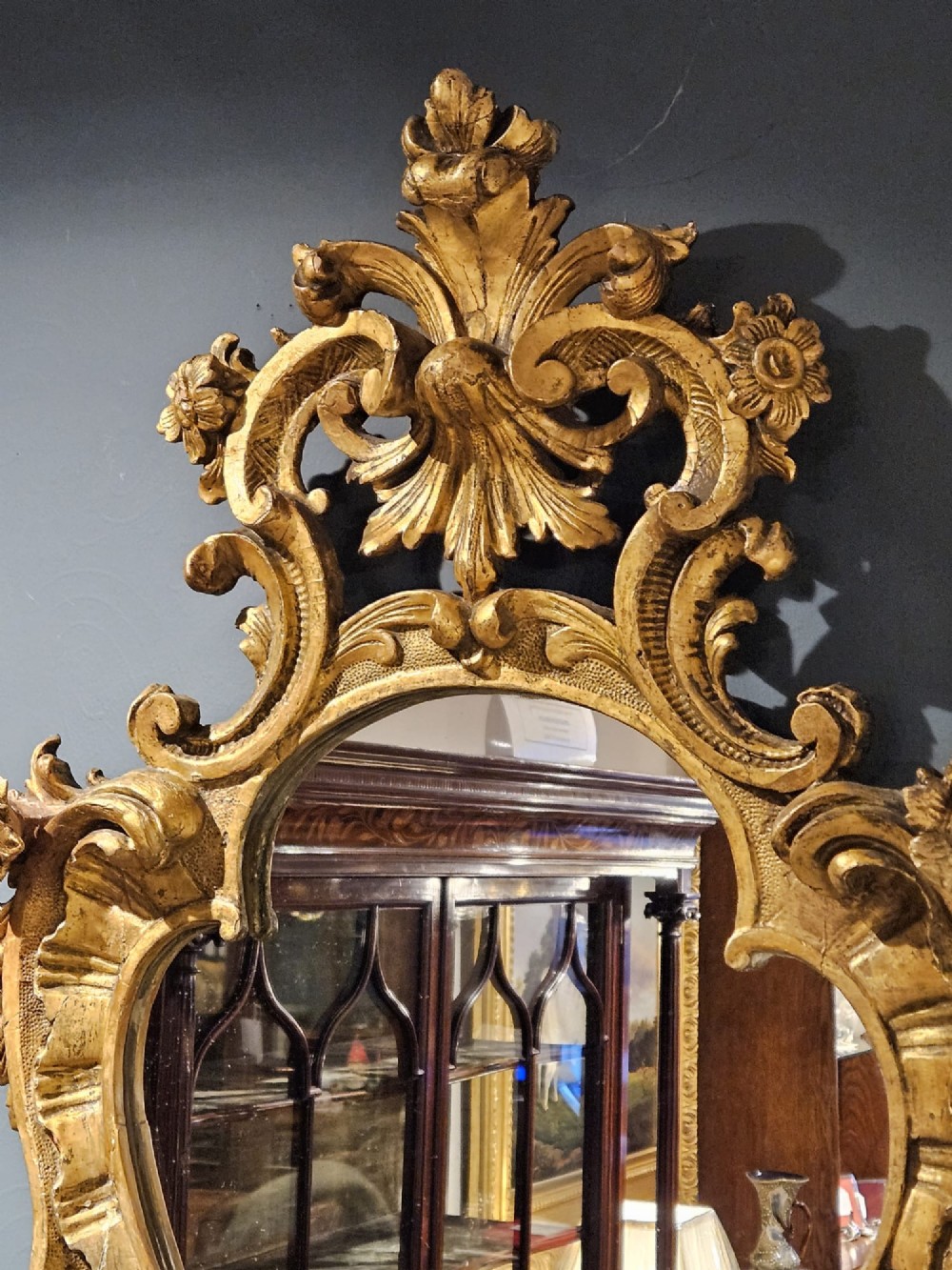 A mid-Victorian lozenge-shaped wall mirror featuring an ornate gold leaf giltwood frame decorated with scrolls and acanthus leaf cresting. View II