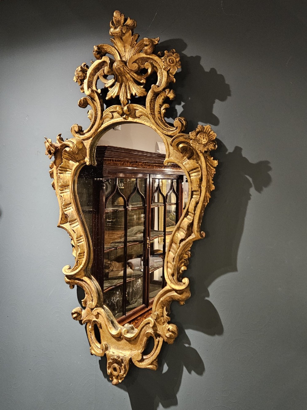 A mid-Victorian lozenge-shaped wall mirror featuring an ornate gold leaf giltwood frame decorated with scrolls and acanthus leaf cresting. View V