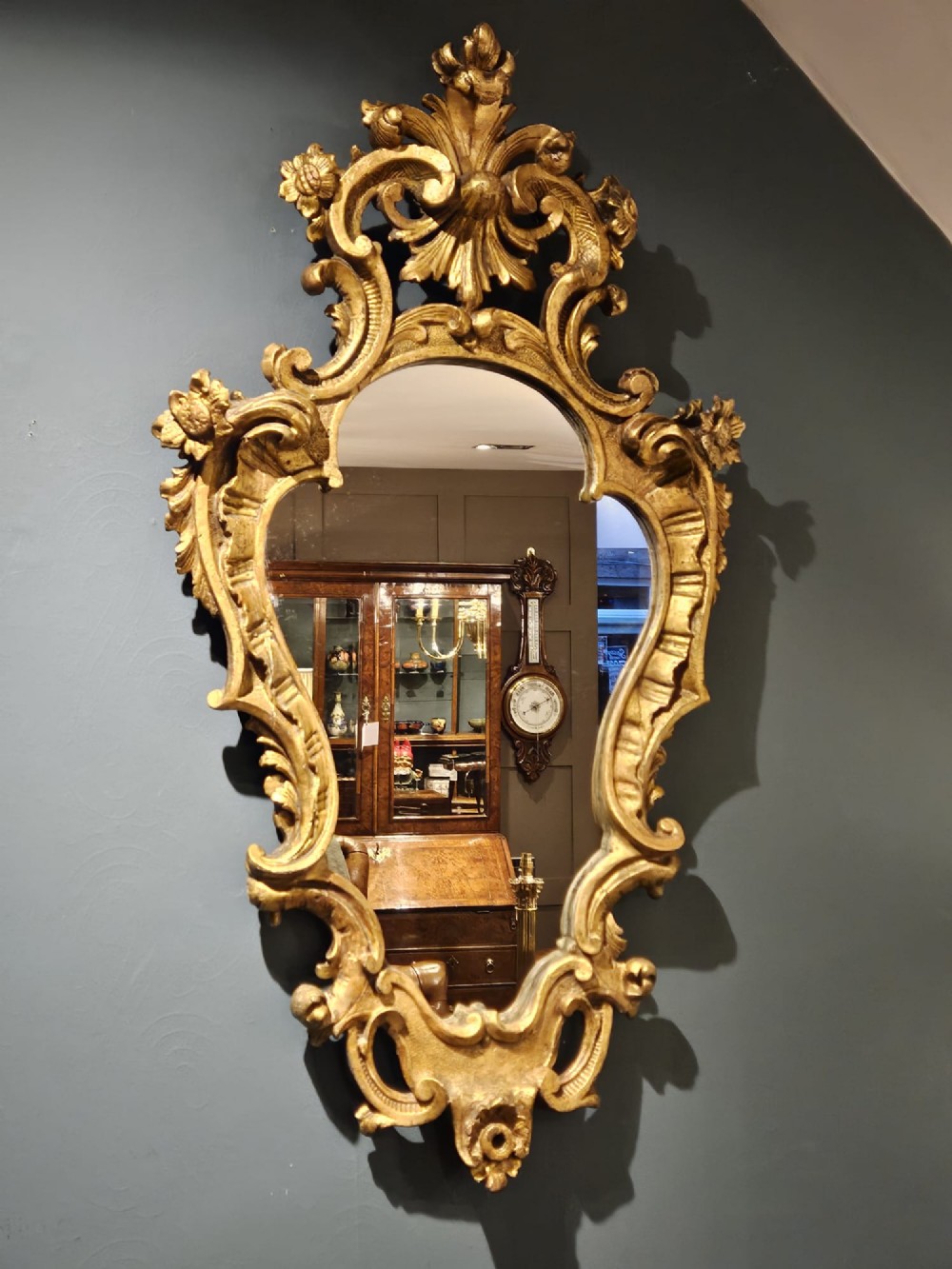 A mid-Victorian lozenge-shaped wall mirror featuring an ornate gold leaf giltwood frame decorated with scrolls and acanthus leaf cresting. View VI