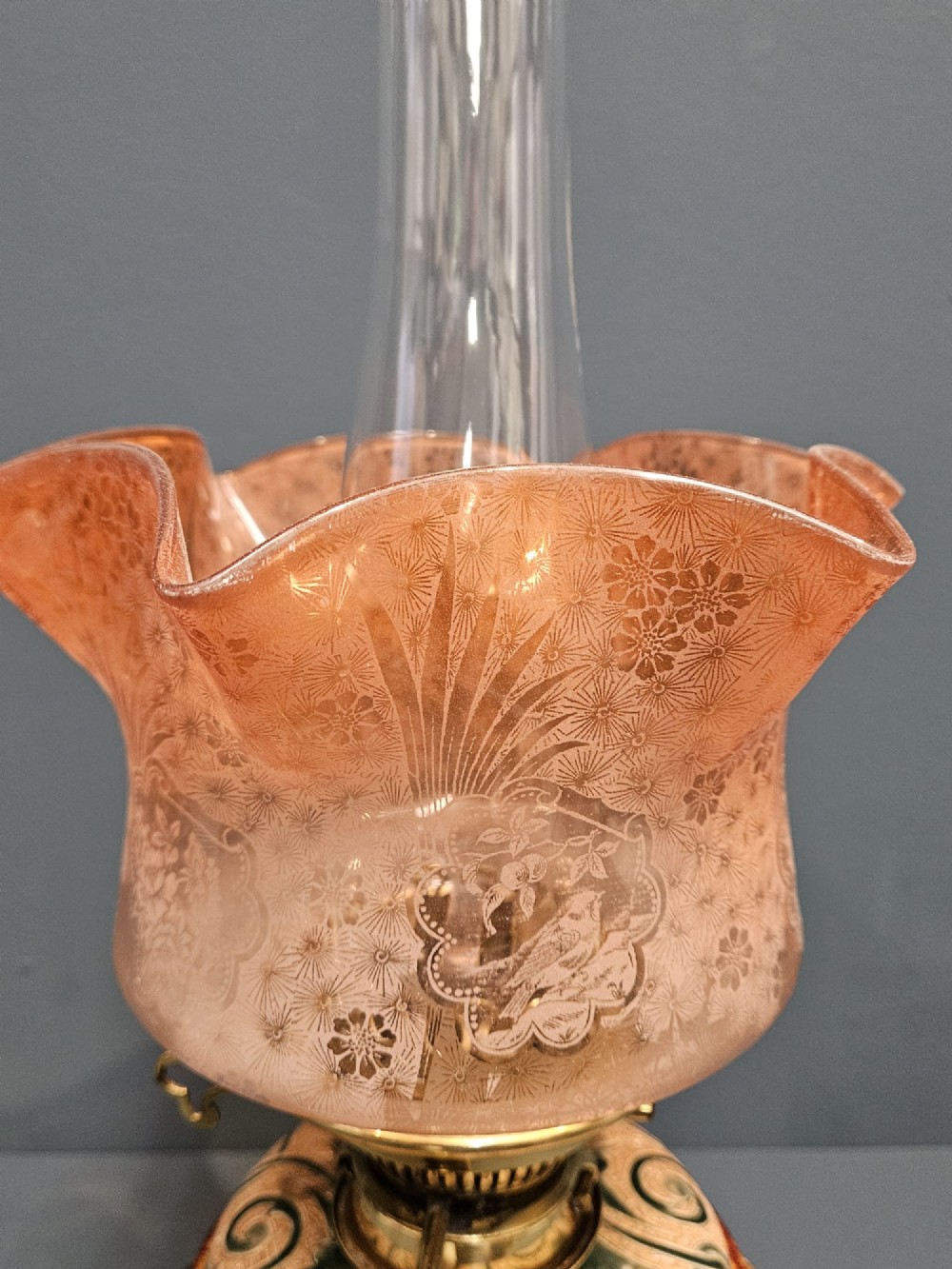 A Victorian Doulton Lambeth stoneware oil lamp featuring an incised ceramic base on claw feet, a brass burner, a glass chimney, and a frilled pink etched shade. View III
