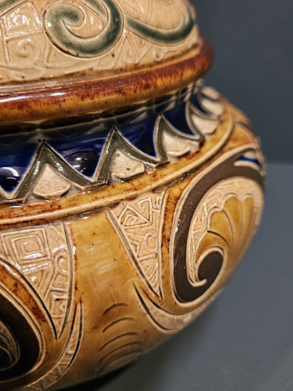 A Victorian Doulton Lambeth stoneware oil lamp featuring an incised ceramic base on claw feet, a brass burner, a glass chimney, and a frilled pink etched shade. View VIII