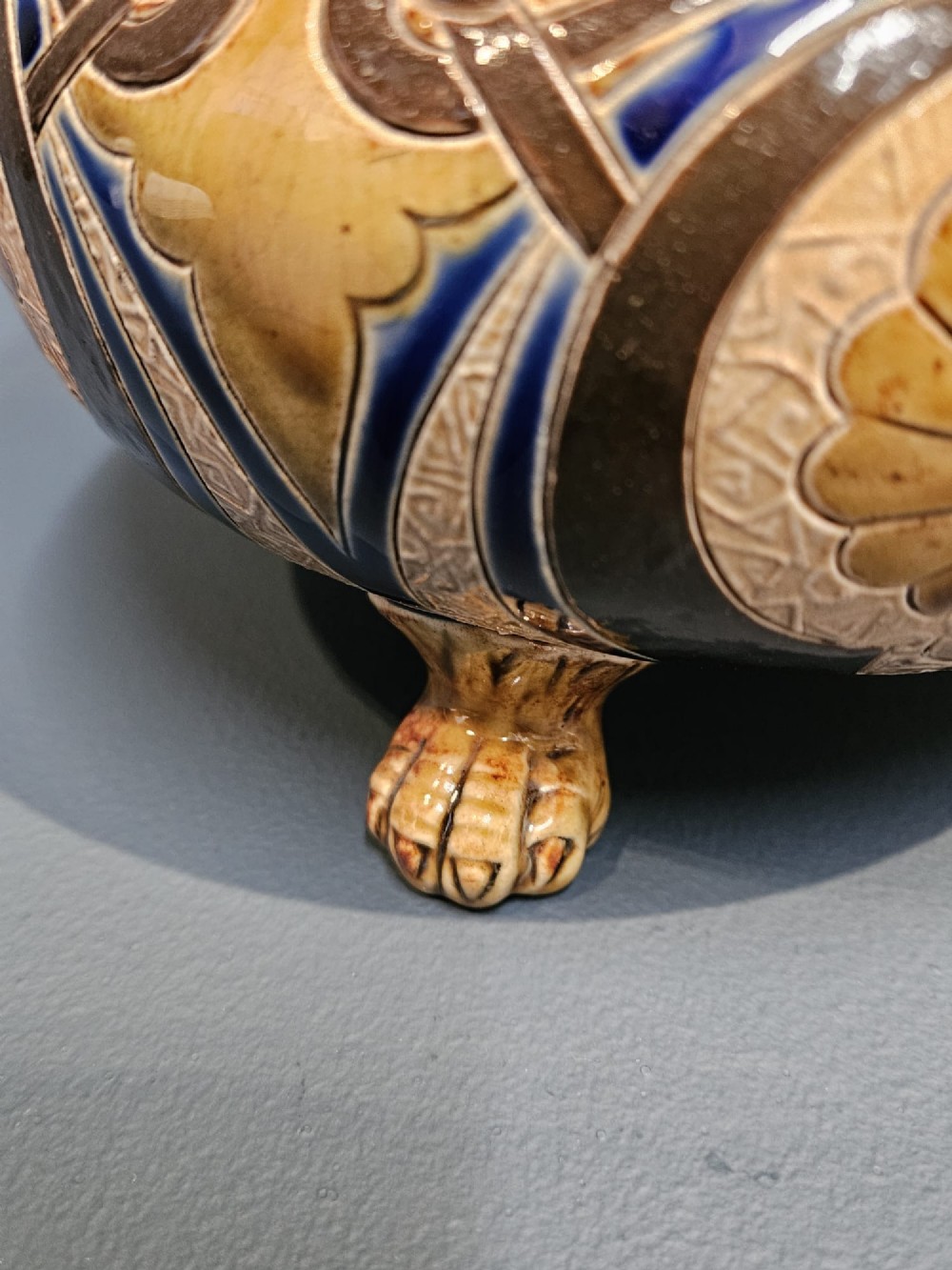 A Victorian Doulton Lambeth stoneware oil lamp featuring an incised ceramic base on claw feet, a brass burner, a glass chimney, and a frilled pink etched shade. View IX