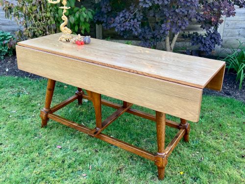 fig 2. A solid medium oak Arts and Crafts refectory dining table with drop-leaf sides, turned angled legs, and a low stretcher base.