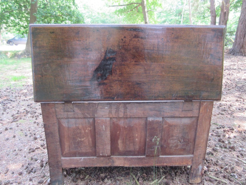 A mid-17th-century dark oak coffer featuring a flat hinged lid, triple-panelled front with split-baluster detail, and sturdy stile legs. View VIII