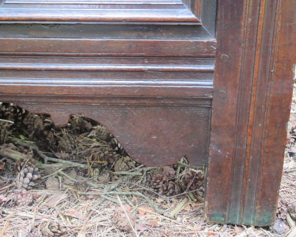 A mid-17th-century dark oak coffer featuring a flat hinged lid, triple-panelled front with split-baluster detail, and sturdy stile legs. View IX