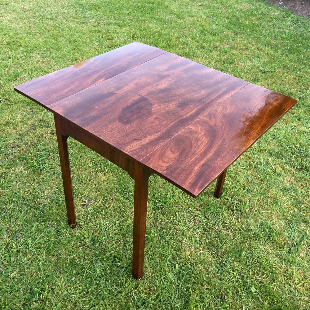 A Georgian mahogany Pembroke table featuring two drop-leaf sides and four square tapered legs.
