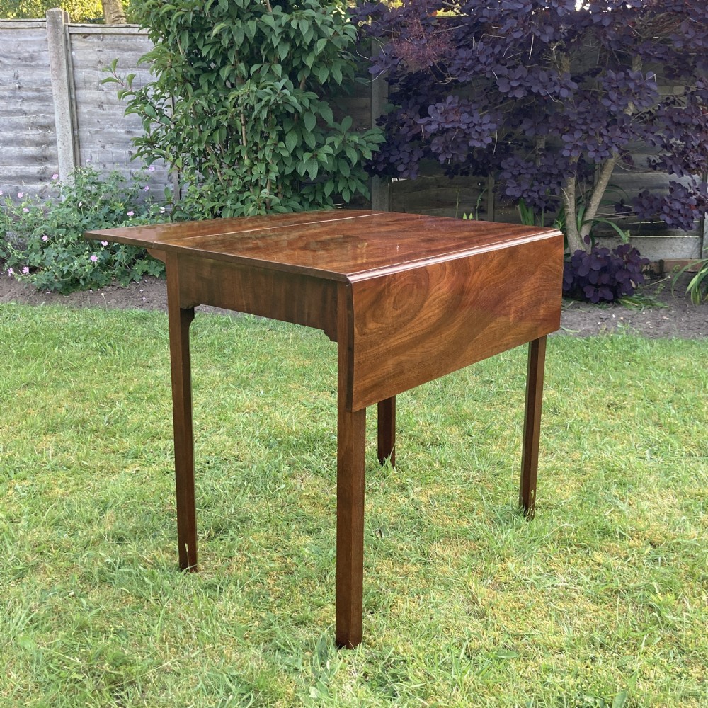 A Georgian mahogany Pembroke table featuring two drop-leaf sides and four square tapered legs. View V