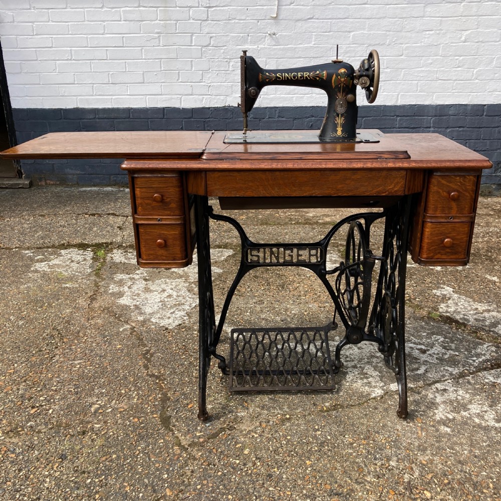 An oak-cased Singer sewing machine side table with side drawers mounted on a black cast iron treadle base. View II