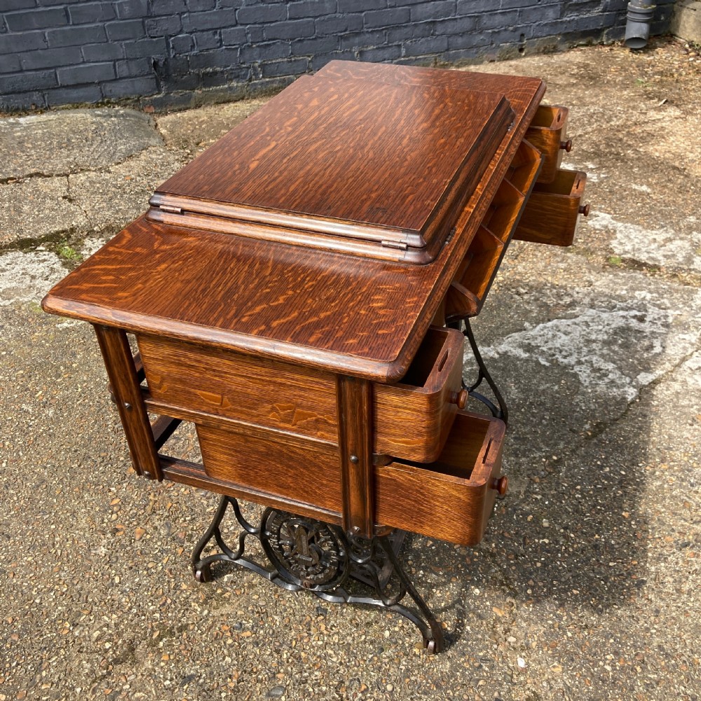 An oak-cased Singer sewing machine side table with side drawers mounted on a black cast iron treadle base. View VII