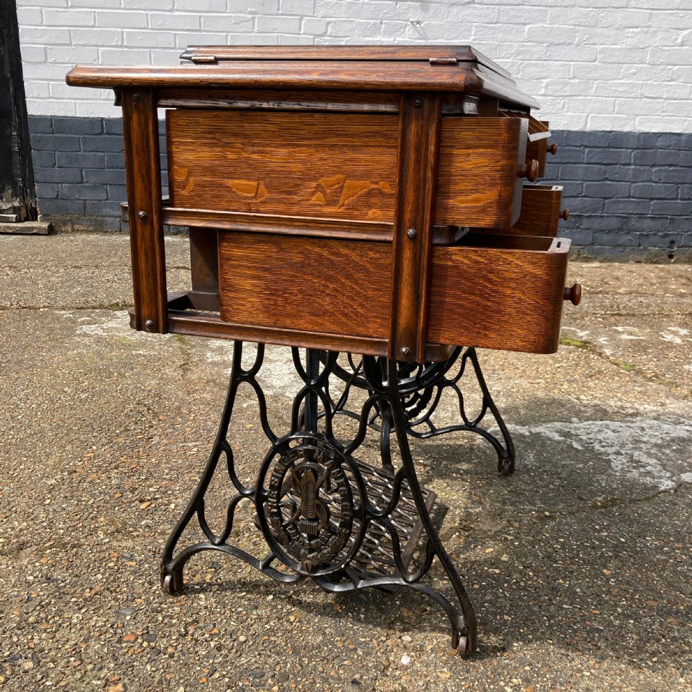 An oak-cased Singer sewing machine side table with side drawers mounted on a black cast iron treadle base. View VIII