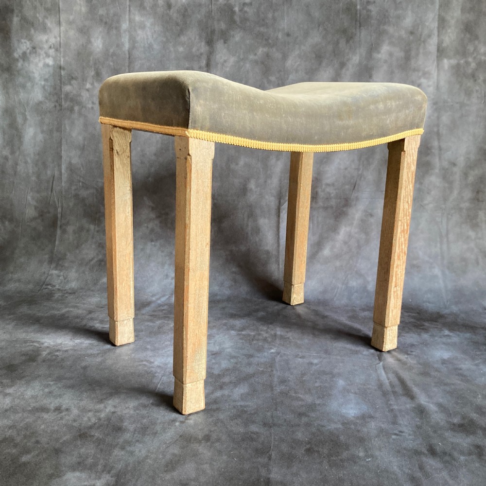 A 1937 King George VI coronation stool featuring a limed oak frame, chamfered legs, and a concave velvet seat edged with gold braid.