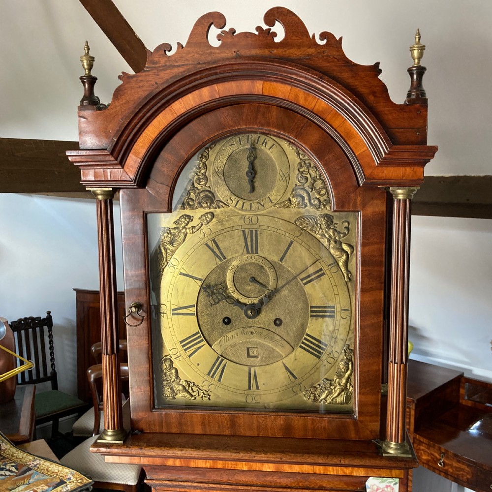 A mid-18th-century Georgian mahogany longcase clock with brass finials, an arched brass dial, and fan marquetry inlay on the door and base. View II