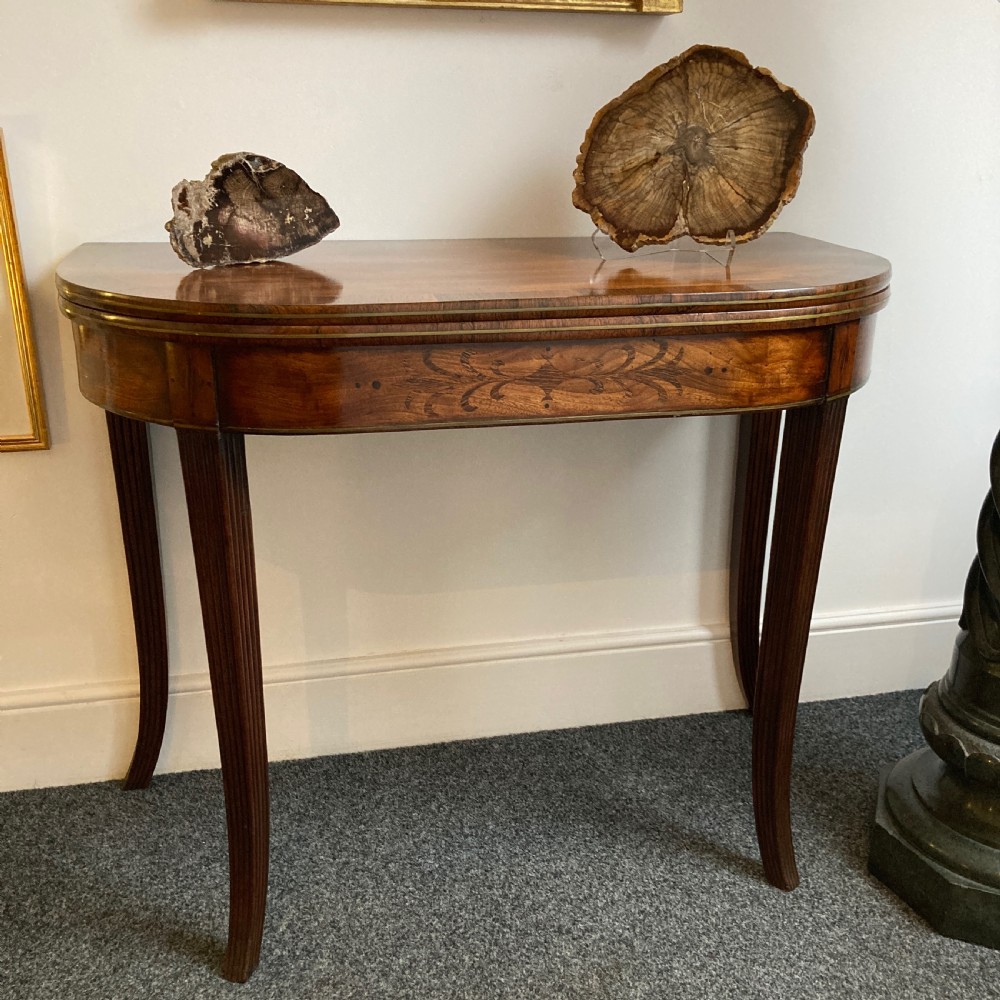 A late Georgian mahogany fold-over tea table featuring an inlaid apron and four reeded legs.