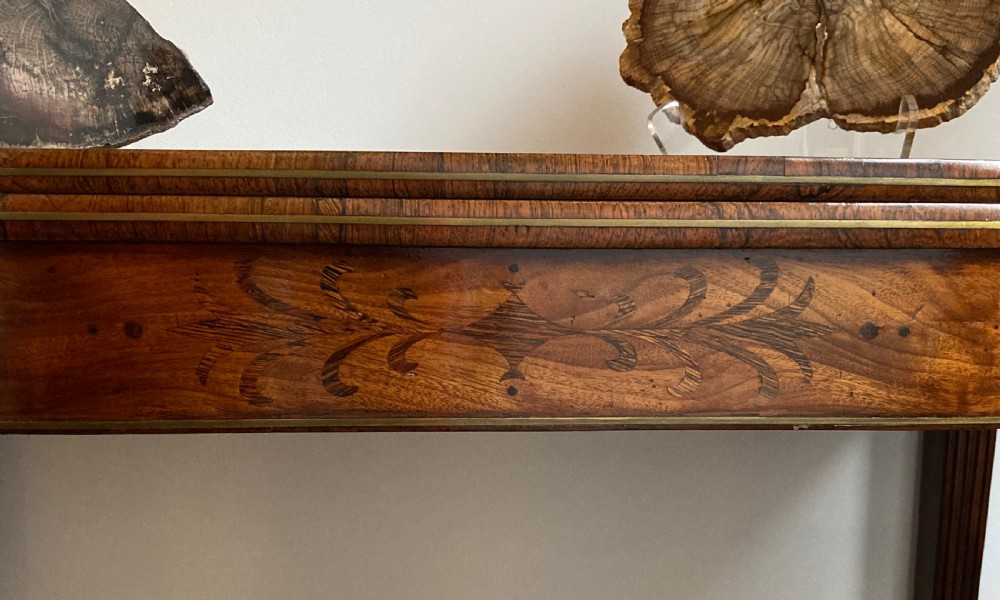 A late Georgian mahogany fold-over tea table featuring an inlaid apron and four reeded legs. View V
