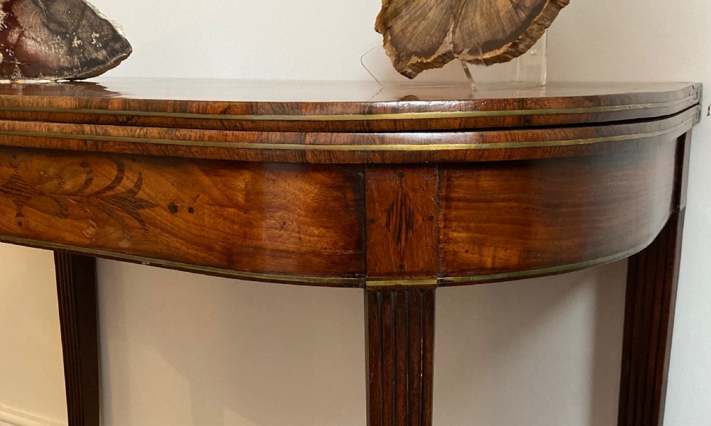 A late Georgian mahogany fold-over tea table featuring an inlaid apron and four reeded legs. View VII