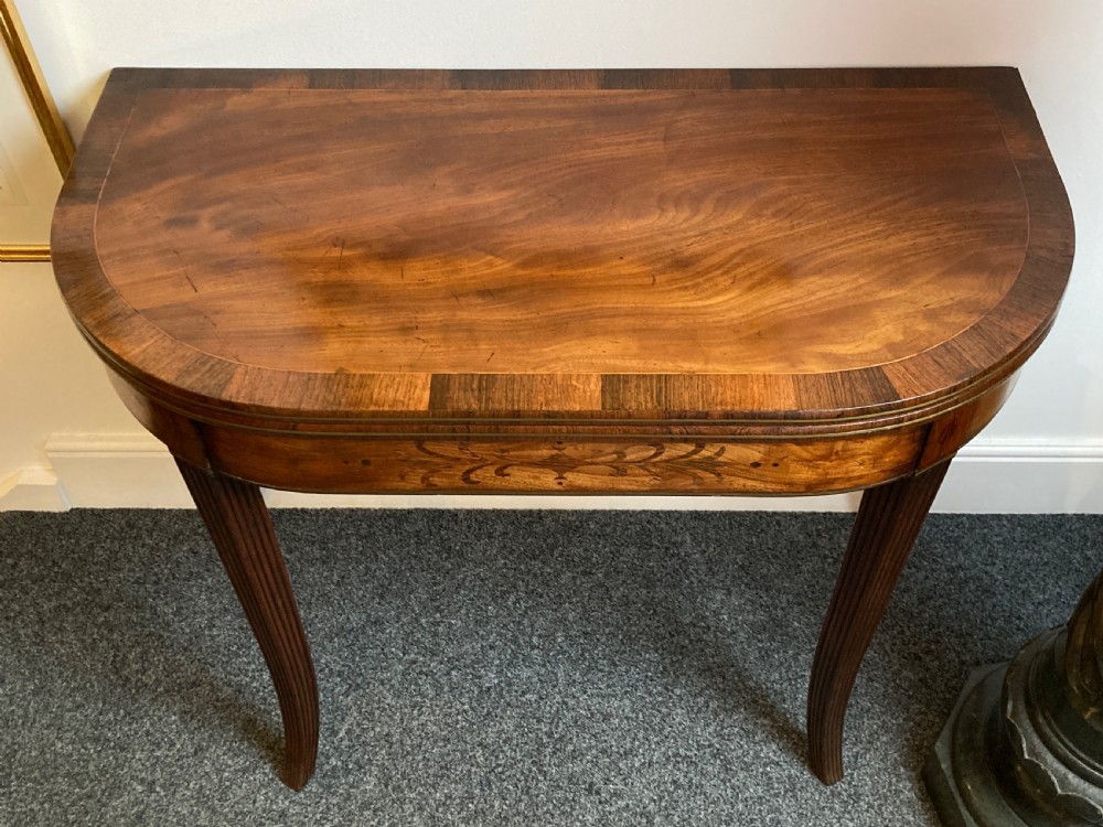 A late Georgian mahogany fold-over tea table featuring an inlaid apron and four reeded legs. View IX