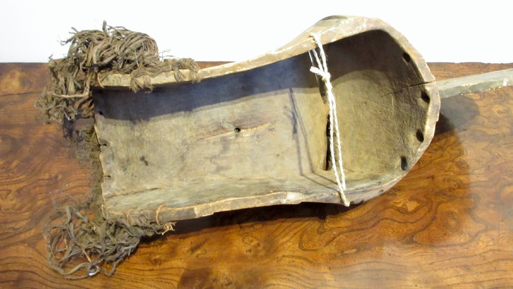 A hand-carved wooden Songye Kifwebe mask featuring a prominent central crest, geometric slitted eyes, a protruded mouth, and a raffia fringe. View VII