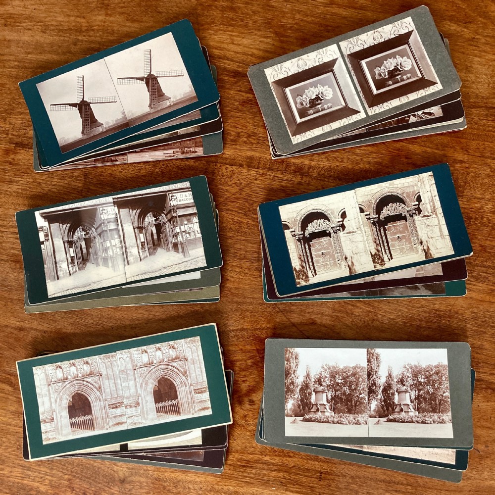 An antique Victorian hinged burr yew wood tabletop stereoscope shown open, featuring dual circular viewing lenses, a central magnifying lens, and a selection of stereoview cards. View XIII