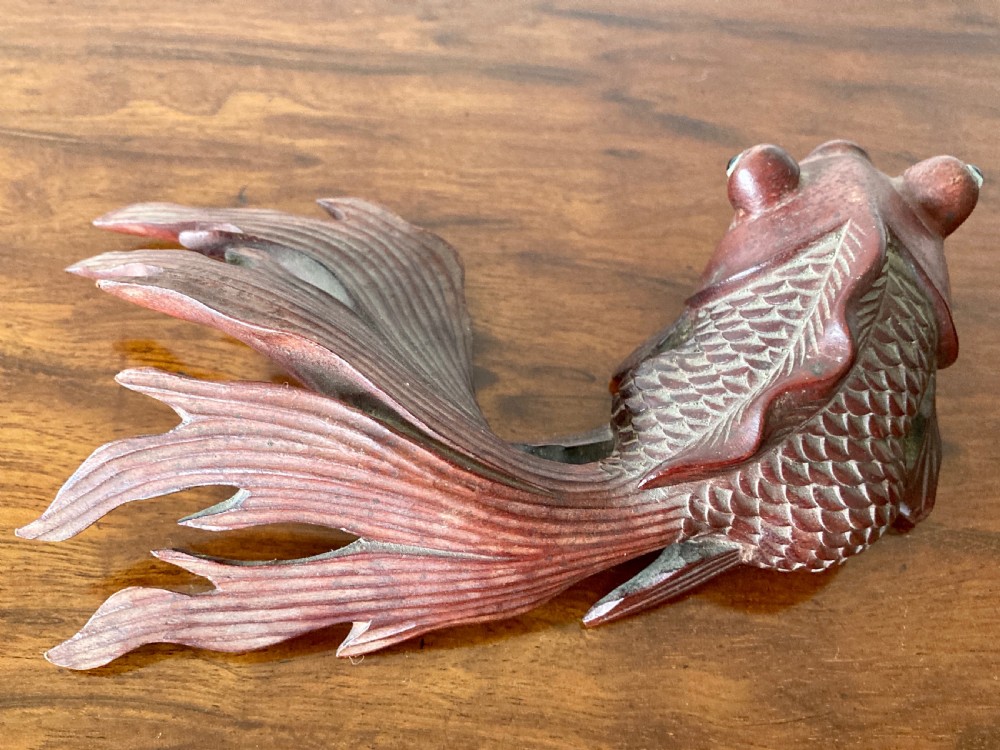 Three 19th-century Oriental carved wooden goldfish figures with detailed scales, flowing fins, and inset glass eyes displayed on a polished surface. View VI