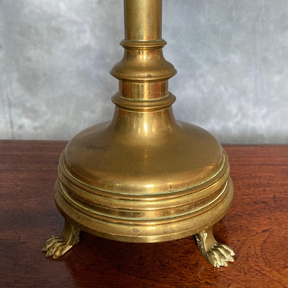 A pair of tall Victorian Gothic Revival cast brass candlesticks featuring pierced crenellated drip pans, knopped stems, and stylized paw feet. View V