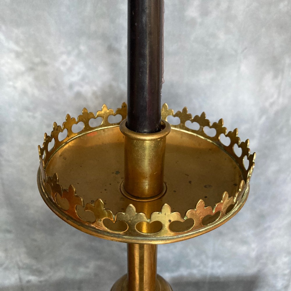 A pair of tall Victorian Gothic Revival cast brass candlesticks featuring pierced crenellated drip pans, knopped stems, and stylized paw feet. View VII
