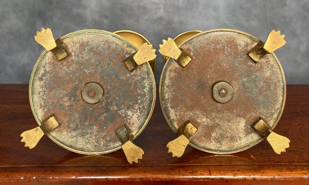 A pair of tall Victorian Gothic Revival cast brass candlesticks featuring pierced crenellated drip pans, knopped stems, and stylized paw feet. View VIII