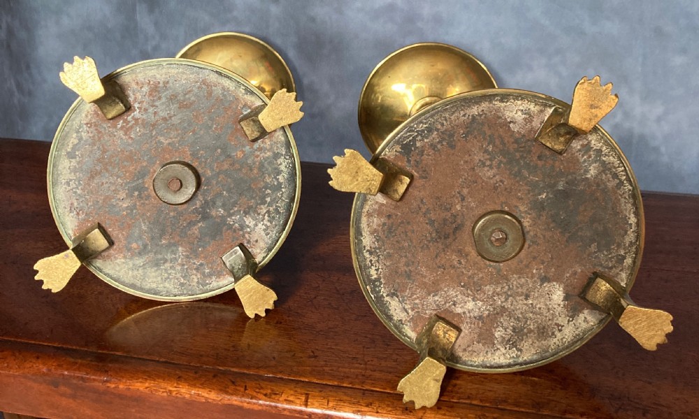 A pair of tall Victorian Gothic Revival cast brass candlesticks featuring pierced crenellated drip pans, knopped stems, and stylized paw feet. View X