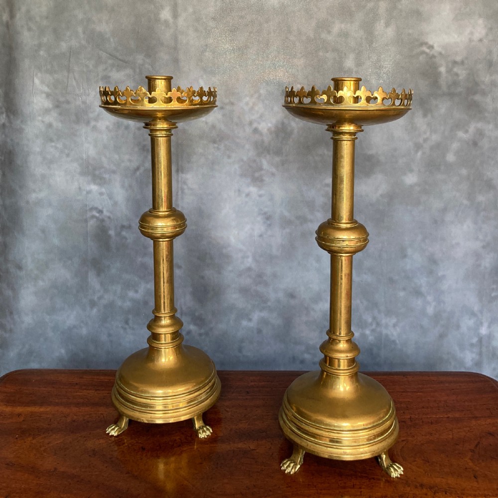 A pair of tall Victorian Gothic Revival cast brass candlesticks featuring pierced crenellated drip pans, knopped stems, and stylized paw feet. View XI