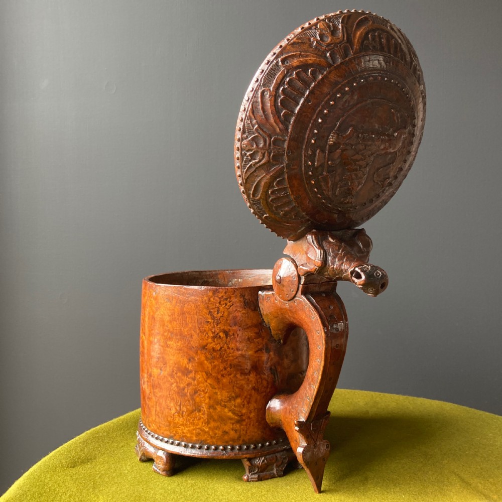 An 18th-century Norwegian carved wooden peg tankard featuring a lion thumbpiece, domed relief-carved lid, and carved lion feet in a warm brown finish. View VII