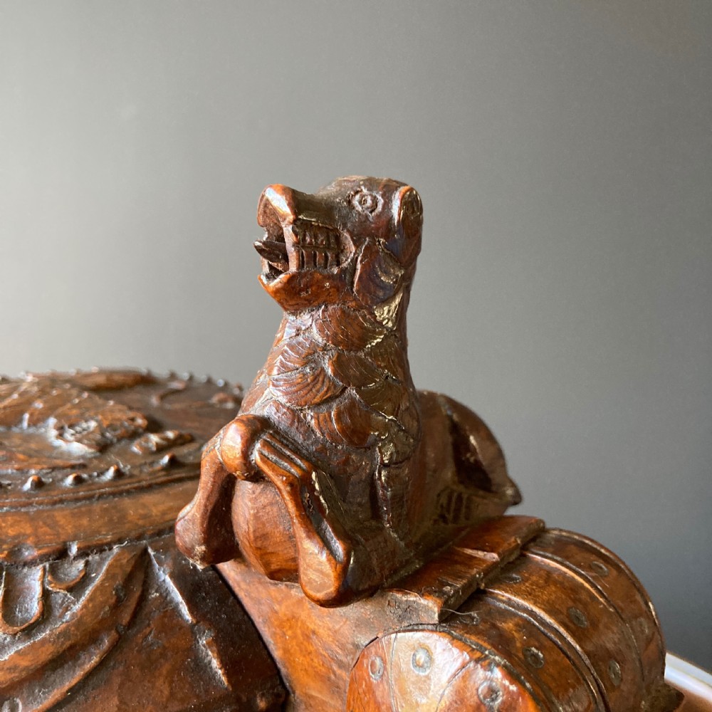 An 18th-century Norwegian carved wooden peg tankard featuring a lion thumbpiece, domed relief-carved lid, and carved lion feet in a warm brown finish. View XI