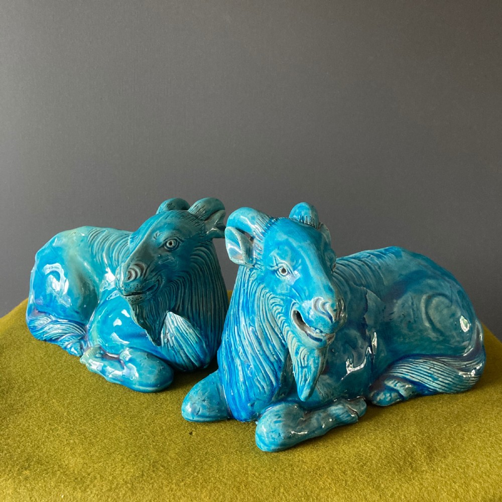 A pair of nineteenth-century Chinese porcelain recumbent goats featuring vibrant turquoise blue monochrome glazing and incised fur detailing.