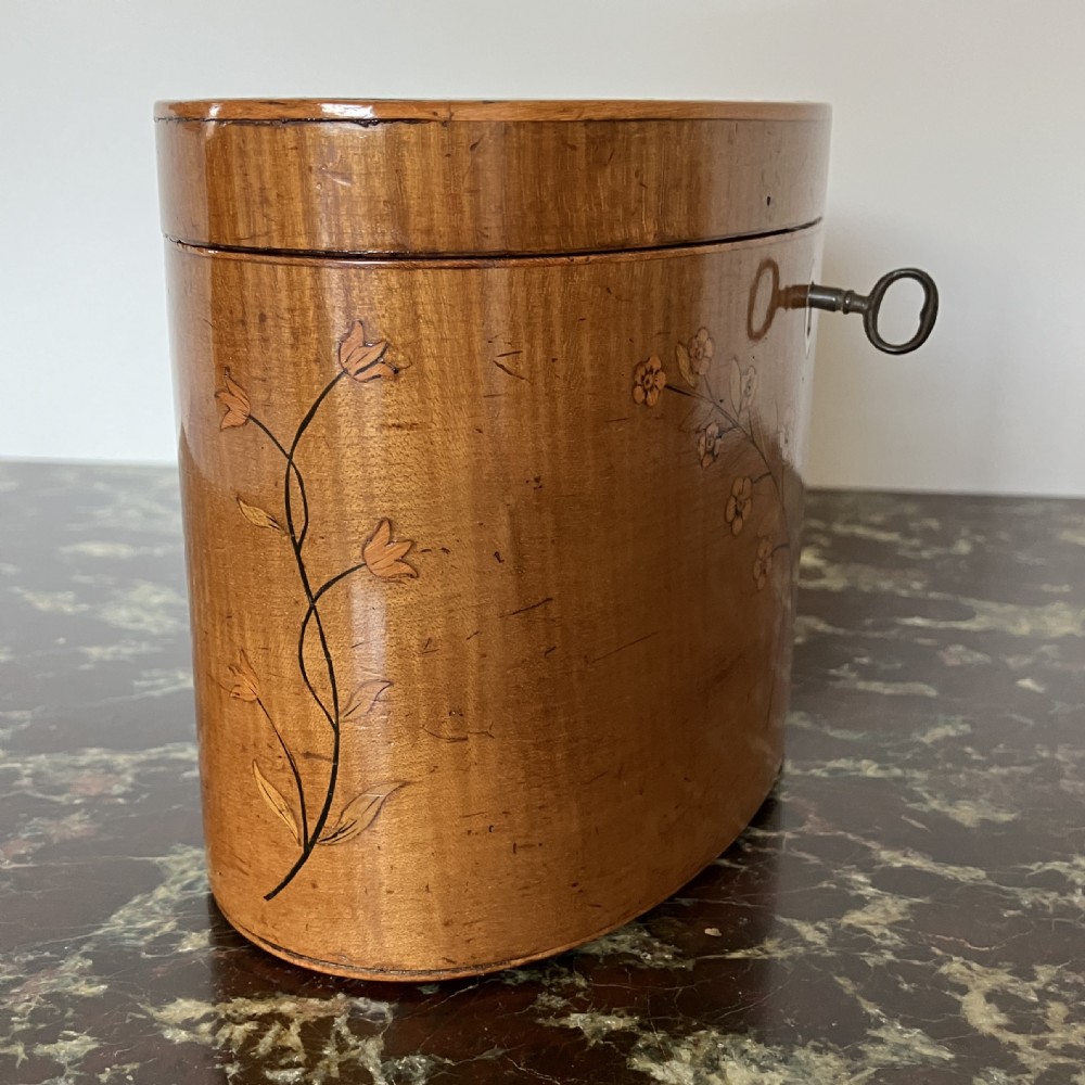 An oval George III satinwood tea caddy featuring floral marquetry inlay on the front, a top medallion motif, and an escutcheon with a key. View III