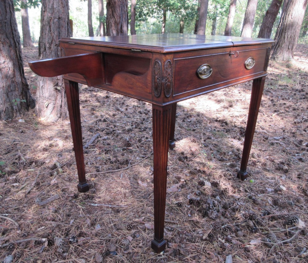 A George III mahogany estate rent table featuring an adjustable leather writing slope, document compartments, side flap extensions, and fluted legs. View VIII