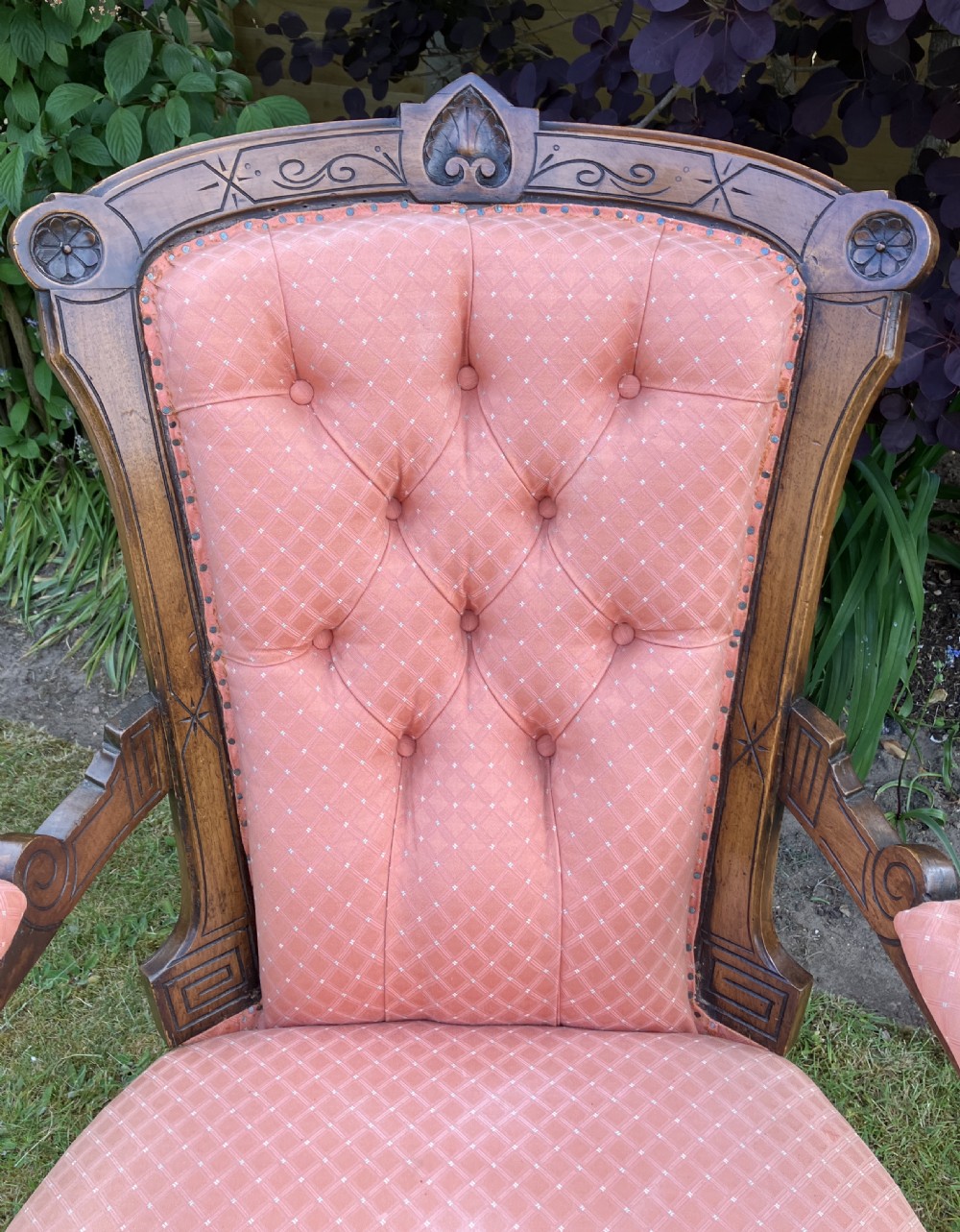 A Victorian walnut open armchair featuring pink patterned button-backed upholstery, a carved wood frame, and turned legs on castors. View II