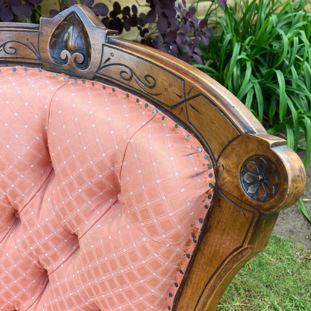 A Victorian walnut open armchair featuring pink patterned button-backed upholstery, a carved wood frame, and turned legs on castors. View III