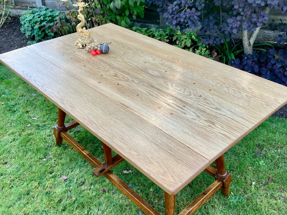A solid oak Arts and Crafts refectory dining table featuring drop-leaf extensions, turned legs, and an H-stretcher base. View VI
