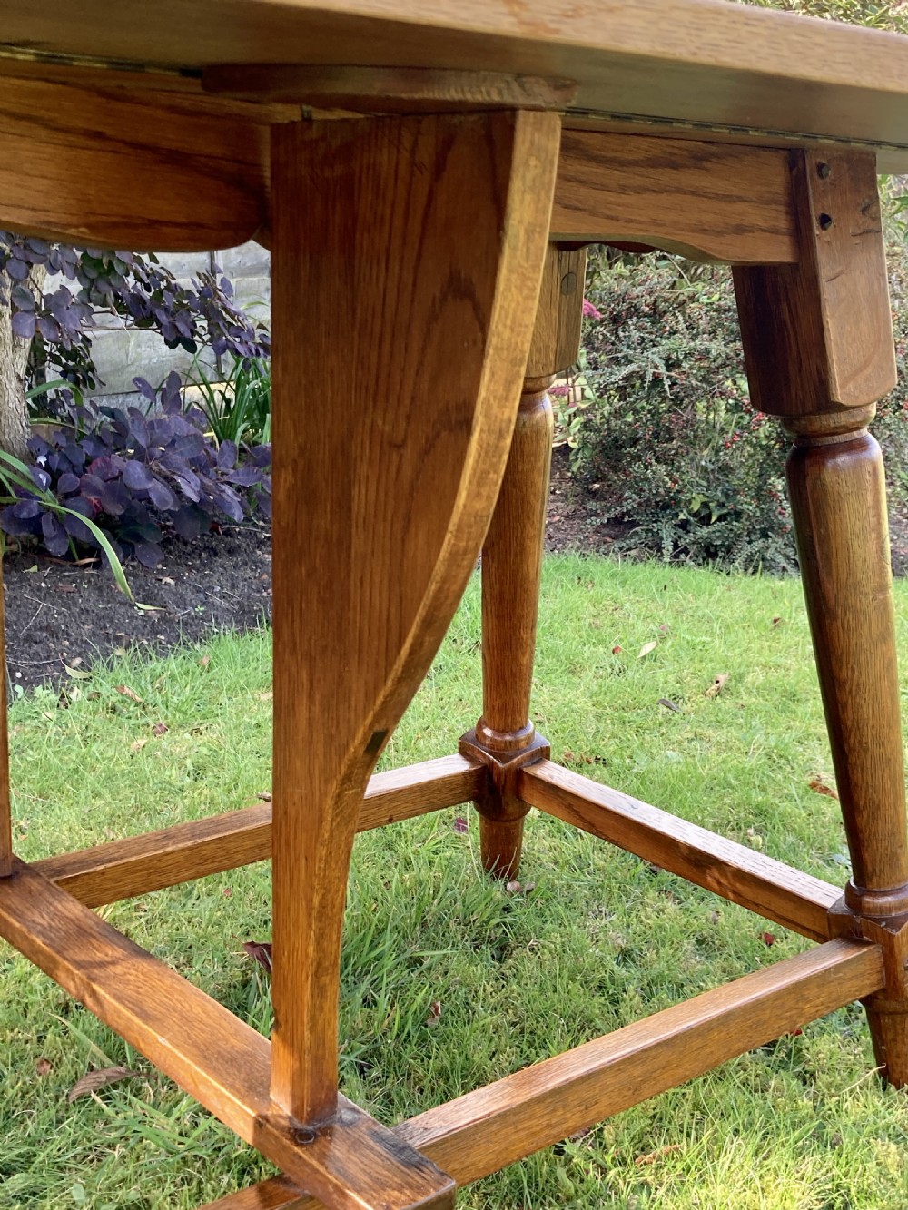 A solid oak Arts and Crafts refectory dining table featuring drop-leaf extensions, turned legs, and an H-stretcher base. View VIII