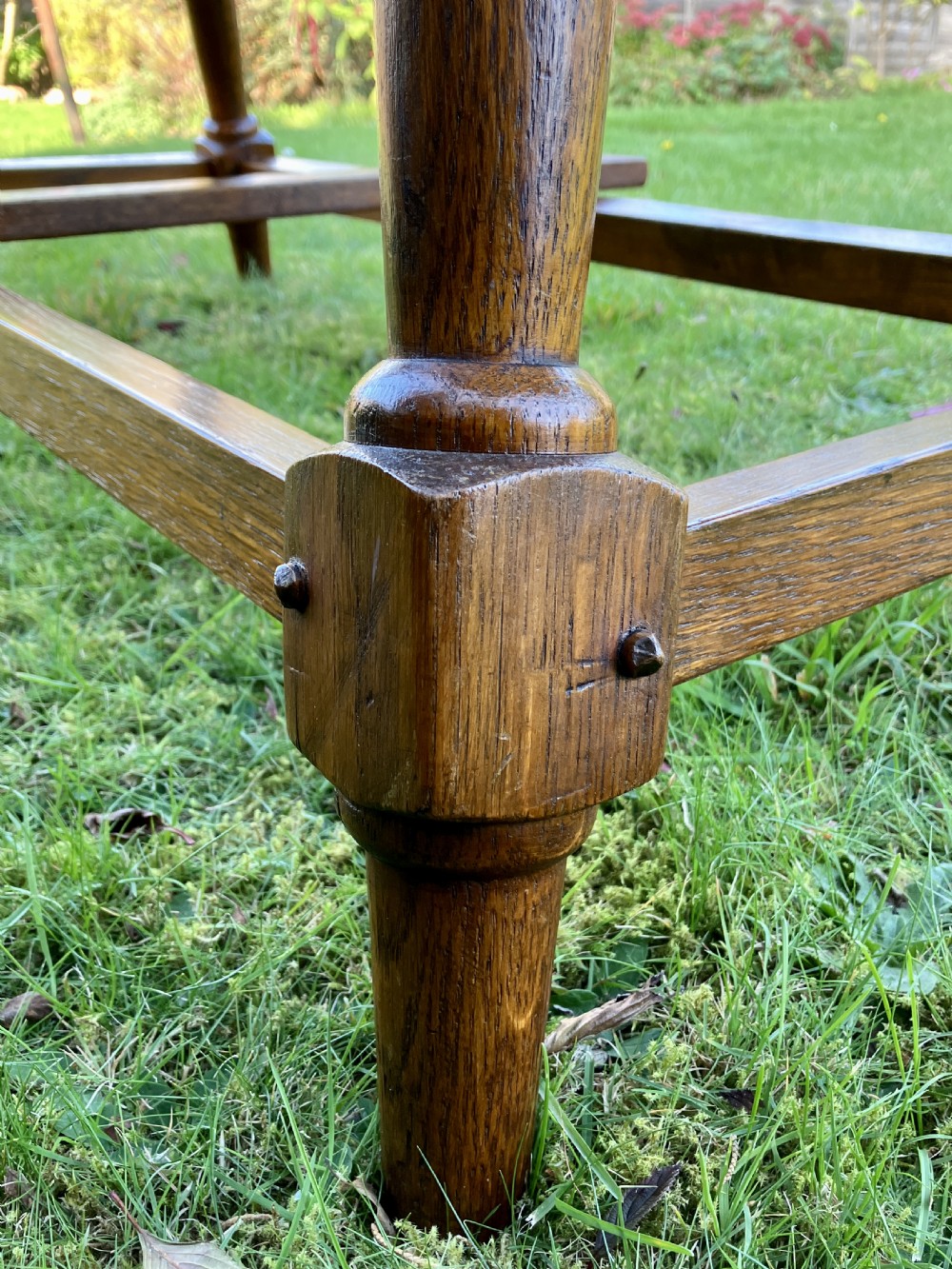A solid oak Arts and Crafts refectory dining table featuring drop-leaf extensions, turned legs, and an H-stretcher base. View XII
